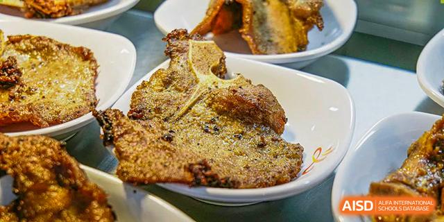 A T-bone steak or large cut of meat served on a white plate in the dining facilities of Guangdong Experimental High School IFPAD & A-Level.