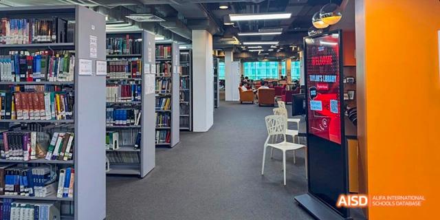 An interior view of a modern library with rows of bookshelves, seating, and computer areas, at Beanstalk International Bilingual School.