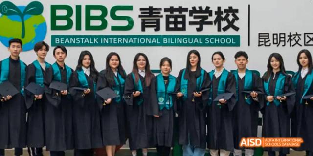 A group of female students wearing black graduation gowns and caps, posing together for a photo, at Beanstalk International Bilingual School.