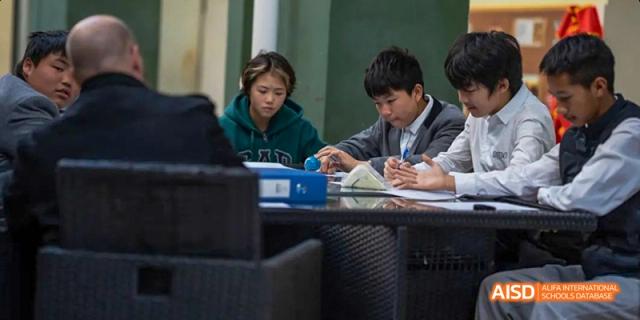 Two students, one male and one female, sitting at an outdoor table working together on schoolwork or a project, at Beanstalk International Bilingual School.