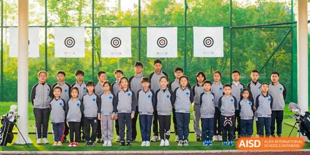 A group of students in matching tracksuits stands in front of archery targets during an outdoor physical education class at Hefei High-tech Sino-Canadian School.