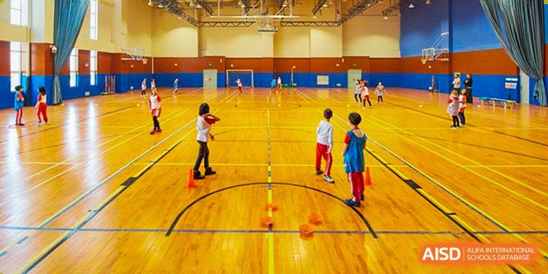 Students participate in an organized physical education class on a brightly lit indoor wooden court at Hefei High-tech Sino-Canadian School.