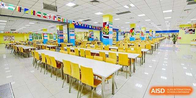 A large, clean school cafeteria features rows of yellow chairs and white tables, ready for the student lunch hour at Hefei High-tech Sino-Canadian School.