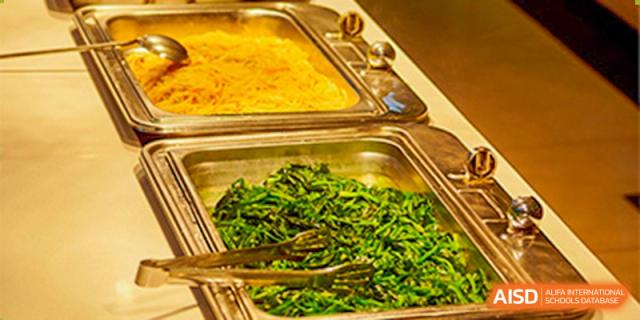 Metal buffet trays in the school cafeteria are filled with fresh noodles and green vegetables for student lunches at Hefei High-tech Sino-Canadian School.