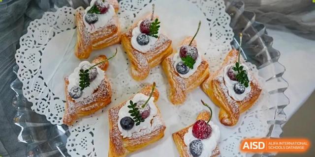 Several elegant puff pastry desserts are topped with fresh blueberries, raspberries, and a dusting of powdered sugar at Hefei High-tech Sino-Canadian School.