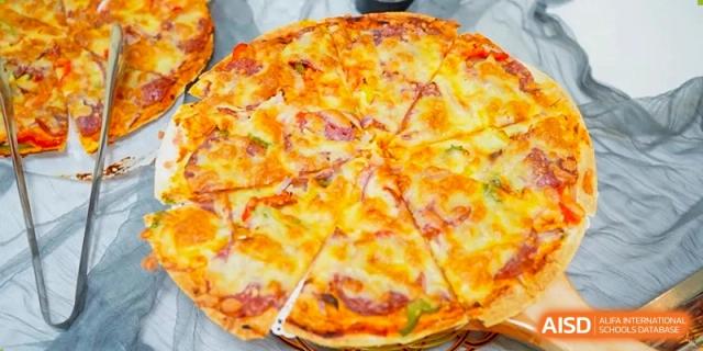 A freshly baked, large thin-crust pizza topped with cheese and savory meats is sliced and ready to be served at Hefei High-tech Sino-Canadian School.