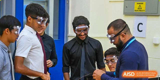 A male student or teacher at The British School of Guangzhou wearing safety goggles and a black shirt, engaged in a hands-on experiment.