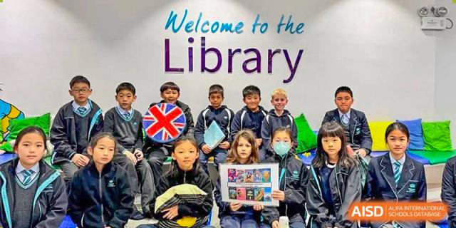 A group of younger students from The British School of Guangzhou posing in front of a "Welcome to the Library" sign.