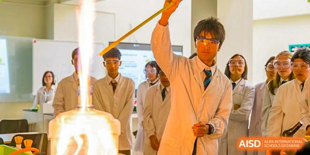 A student at The British School of Guangzhou holding up a long rod during a dramatic science demonstration in the lab.