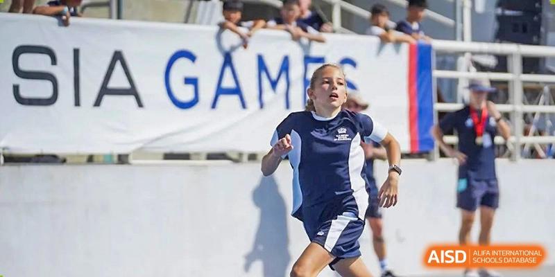 A student from The British School of Guangzhou running in a track event during a school sports day or games competition.