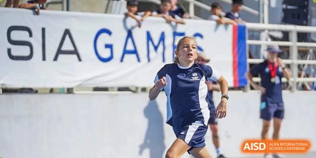 A student from The British School of Guangzhou running in a track event during a school sports day or games competition.