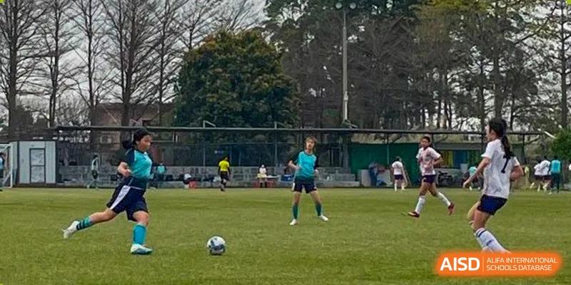 A student from The British School of Guangzhou practicing alone with a football on an outdoor pitch.