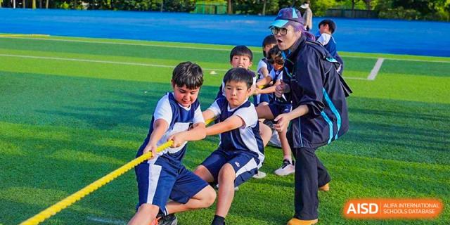 Young students from The British School of Guangzhou competing in a spirited tug-of-war or team game outdoors.