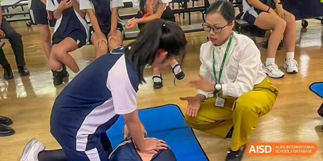 A student from The British School of Guangzhou practicing CPR or first aid on a training dummy during a Health & Nutrition lesson.