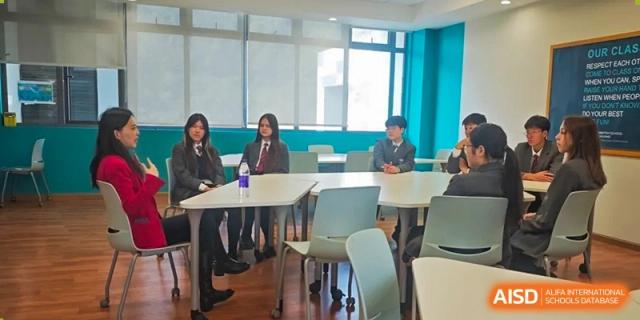 Two students from The British School of Nanjing sitting at a table with laptops in a classroom or library.