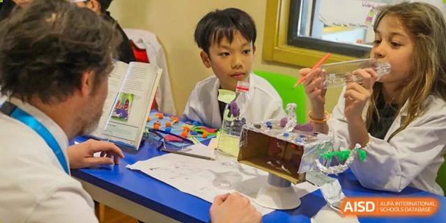 A young student from The British School of Nanjing concentrating while using a device and a tablet in a classroom.