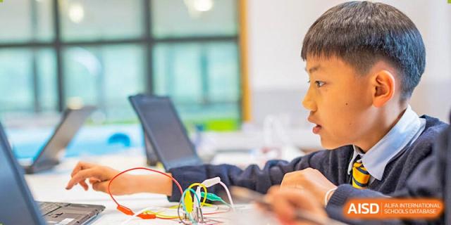 Students from The British School of Nanjing wearing safety goggles and working with equipment in a science lab.