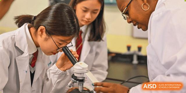 Students from The British School of Nanjing using a microscope for a science experiment.