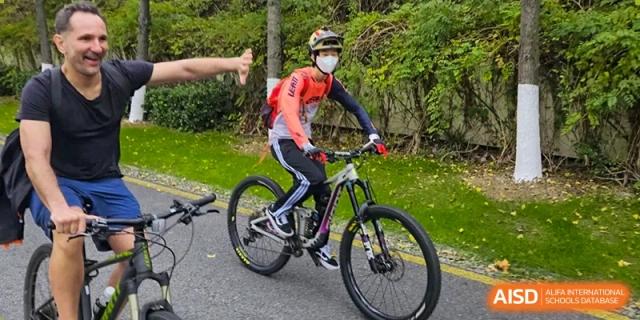 A cyclist from The British School of Nanjing riding a bike on a dirt path in a wooded area.