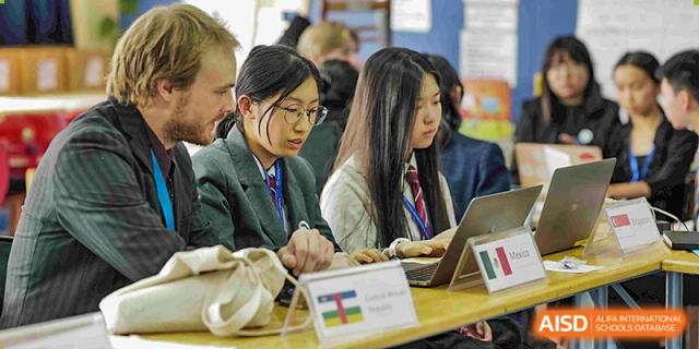 Students from The British School of Nanjing focused on their laptops and notebooks during a class.