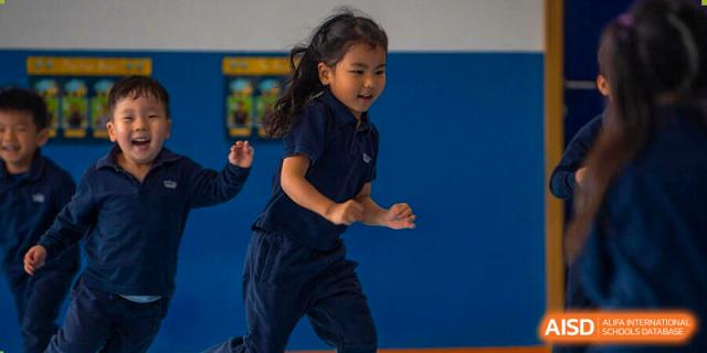 A young student from The British School of Nanjing running or playing a game on a blue indoor court.