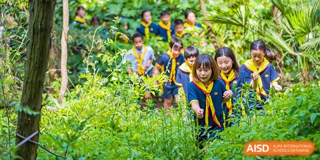 A group of students from The British School of Nanjing in uniform, working in a garden or green space.