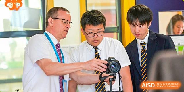 A male teacher and a male student from The British School of Nanjing working with a camera together.