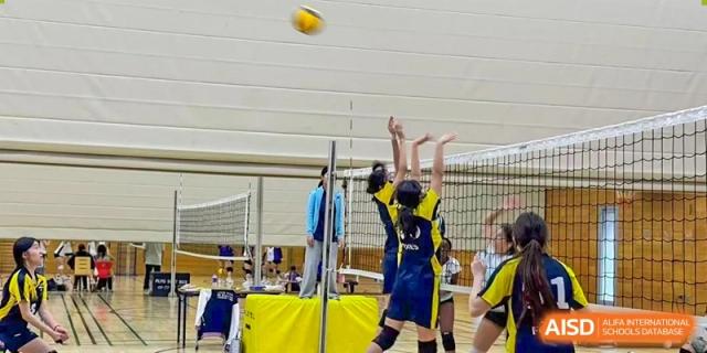 A student from The British School of Nanjing jumping to spike a volleyball during a game.