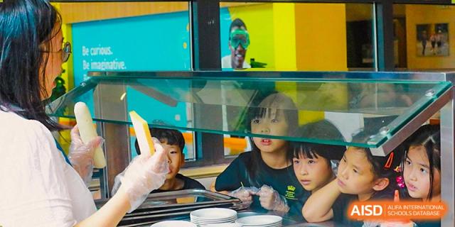 A group of students from The British School of Nanjing sitting at a table with plates of food.