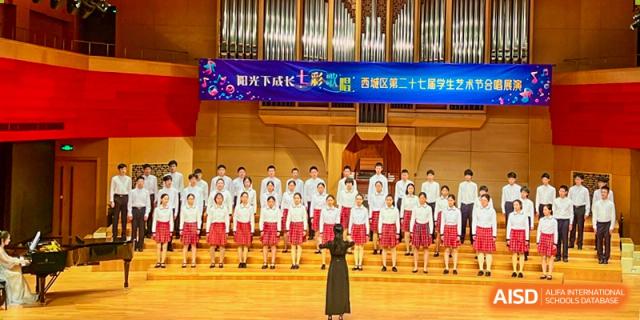 Students from The High School Affiliated To Beijing Normal University singing in a choir with a large pipe organ in the background.