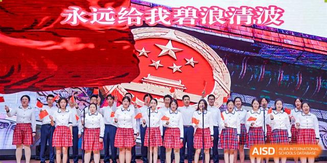 Students from The High School Affiliated To Beijing Normal University posing for a photo on a stage with a banner behind them.