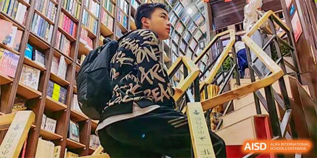 A student from The High School Affiliated To Beijing Normal University with a backpack looking for books in the library.