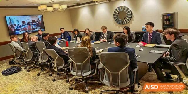 Students and faculty from The High School Affiliated To Beijing Normal University seated around a large table during a meeting.