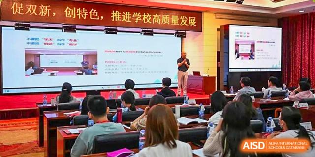 A teacher from The High School Affiliated To Beijing Normal University giving a presentation to a class in a lecture hall.