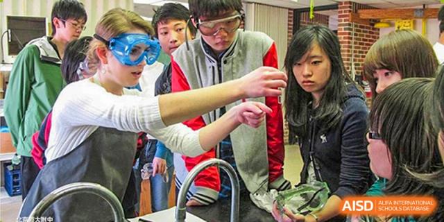 Students from The High School Affiliated To Beijing Normal University wearing goggles and conducting a science experiment in a lab.