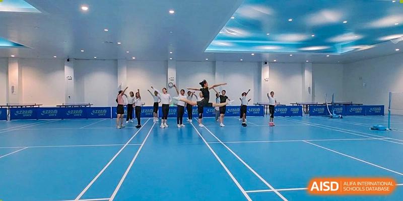 Students from The High School Affiliated To Beijing Normal University practicing dance or exercise in a gymnasium.