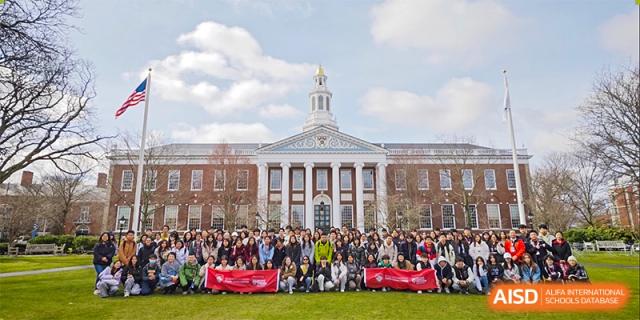 A group of students from The High School Affiliated To Beijing Normal University gathered in front of a large university building.