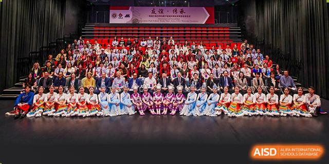 A large group of students from The High School Affiliated To Beijing Normal University posing for a group photo on a stage.