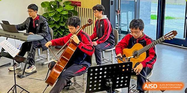 Students from The High School Affiliated To Beijing Normal University playing the cello and guitar outdoors.