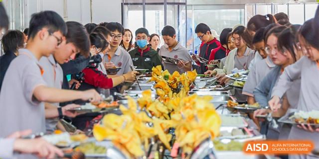 Students from The High School Affiliated To Beijing Normal University getting food from a buffet or serving station.