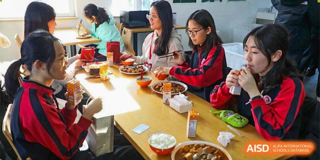 Students from The High School Affiliated To Beijing Normal University eating a meal together at a table.