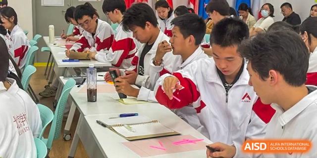 Students from The High School Affiliated to Renmin University of China, Tongzhou Campus, sit at a table and work on a project.