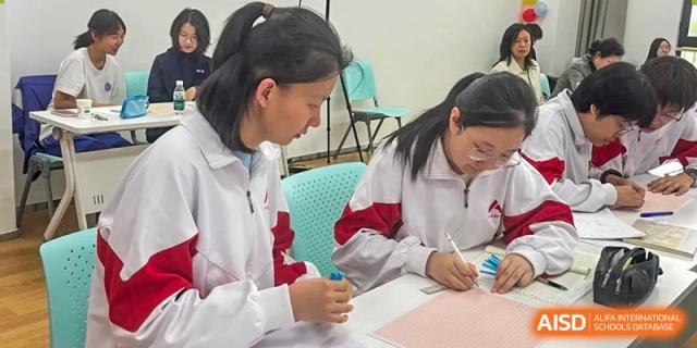 A female student from The High School Affiliated to Renmin University of China, Tongzhou Campus, writes on a notebook in a classroom.