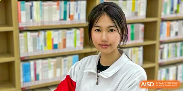 A female student from The High School Affiliated to Renmin University of China, Tongzhou Campus, looks at the camera in a library.