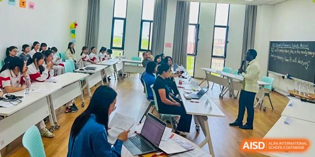 A group of students from The High School Affiliated to Renmin University of China, Tongzhou Campus, works together on laptops in a bright room.