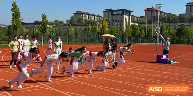 A group of students from The High School Affiliated to Renmin University of China, Tongzhou Campus, participates in a team activity on a track.
