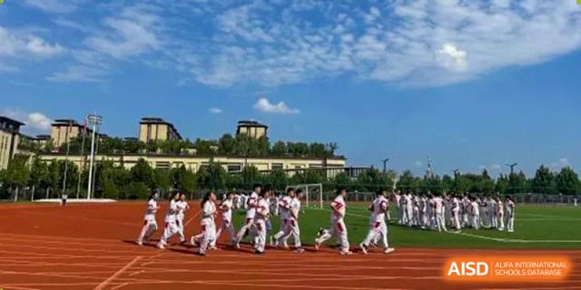 Students from The High School Affiliated to Renmin University of China, Tongzhou Campus, march in formation on an outdoor track.