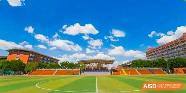 A wide-angle view of a track and field with students and a blue sky from The High School Affiliated to Renmin University of China, Tongzhou Campus.