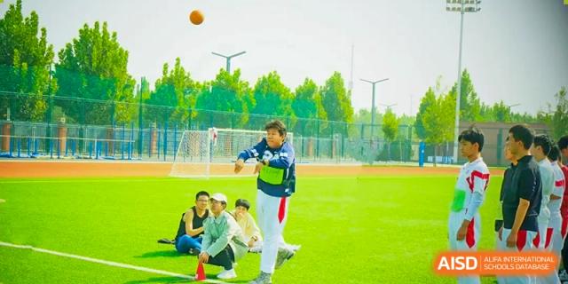 A group of students from The High School Affiliated to Renmin University of China, Tongzhou Campus, with a teacher on a green sports field.