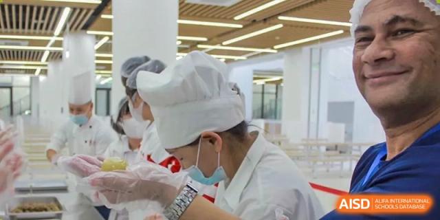 A female student from The High School Affiliated to Renmin University of China, Tongzhou Campus, in a chef's hat, prepares food.